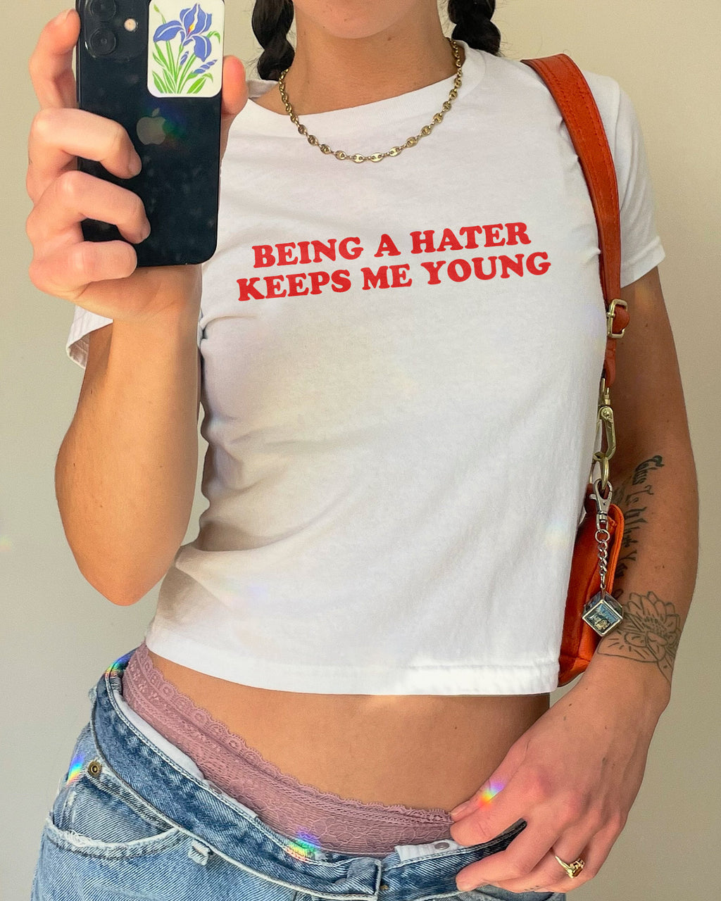Woman wearing white y2k baby tee with funny quote "Being A Hater Keeps Me Young"