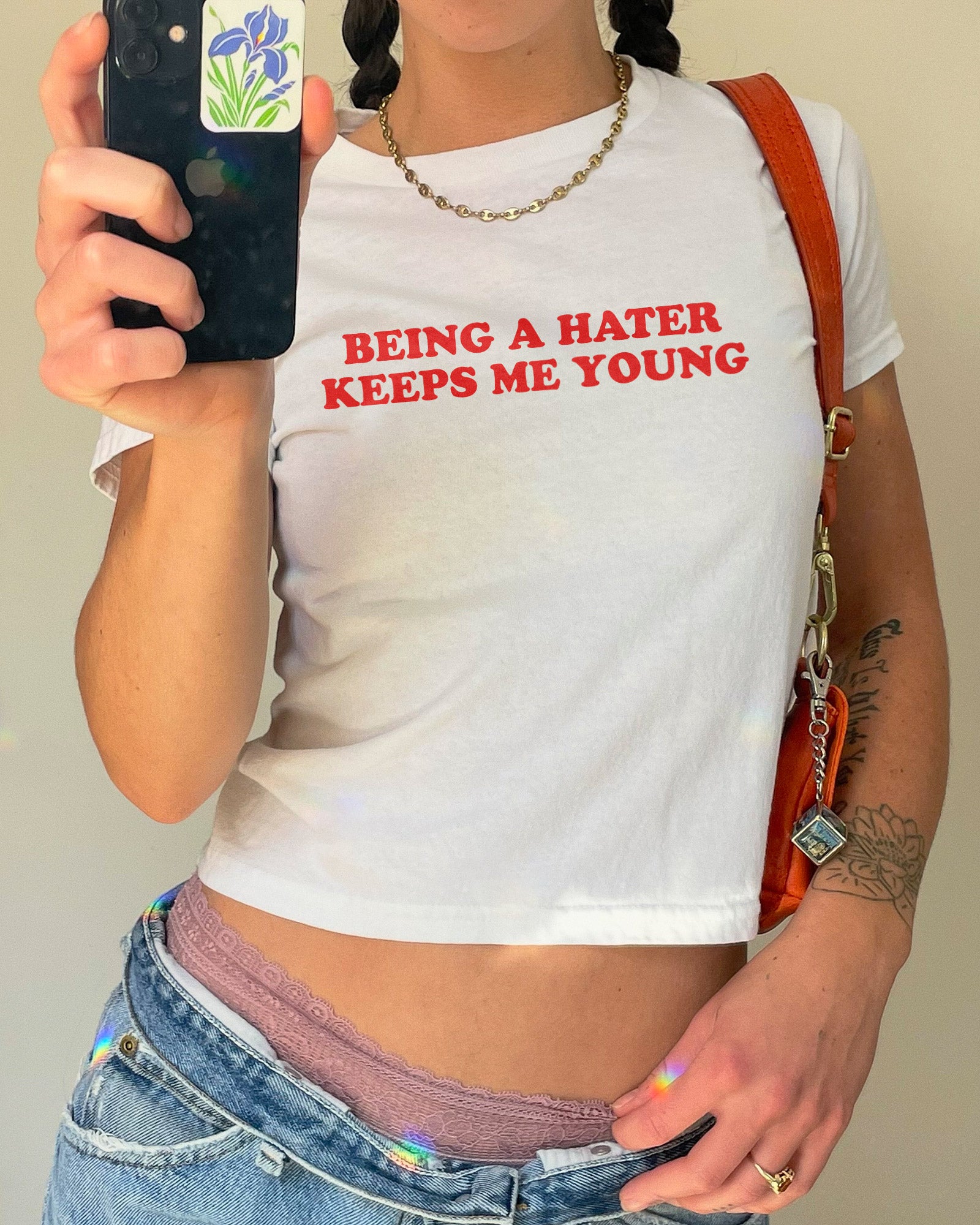 Woman wearing white y2k baby tee with funny quote "Being A Hater Keeps Me Young"